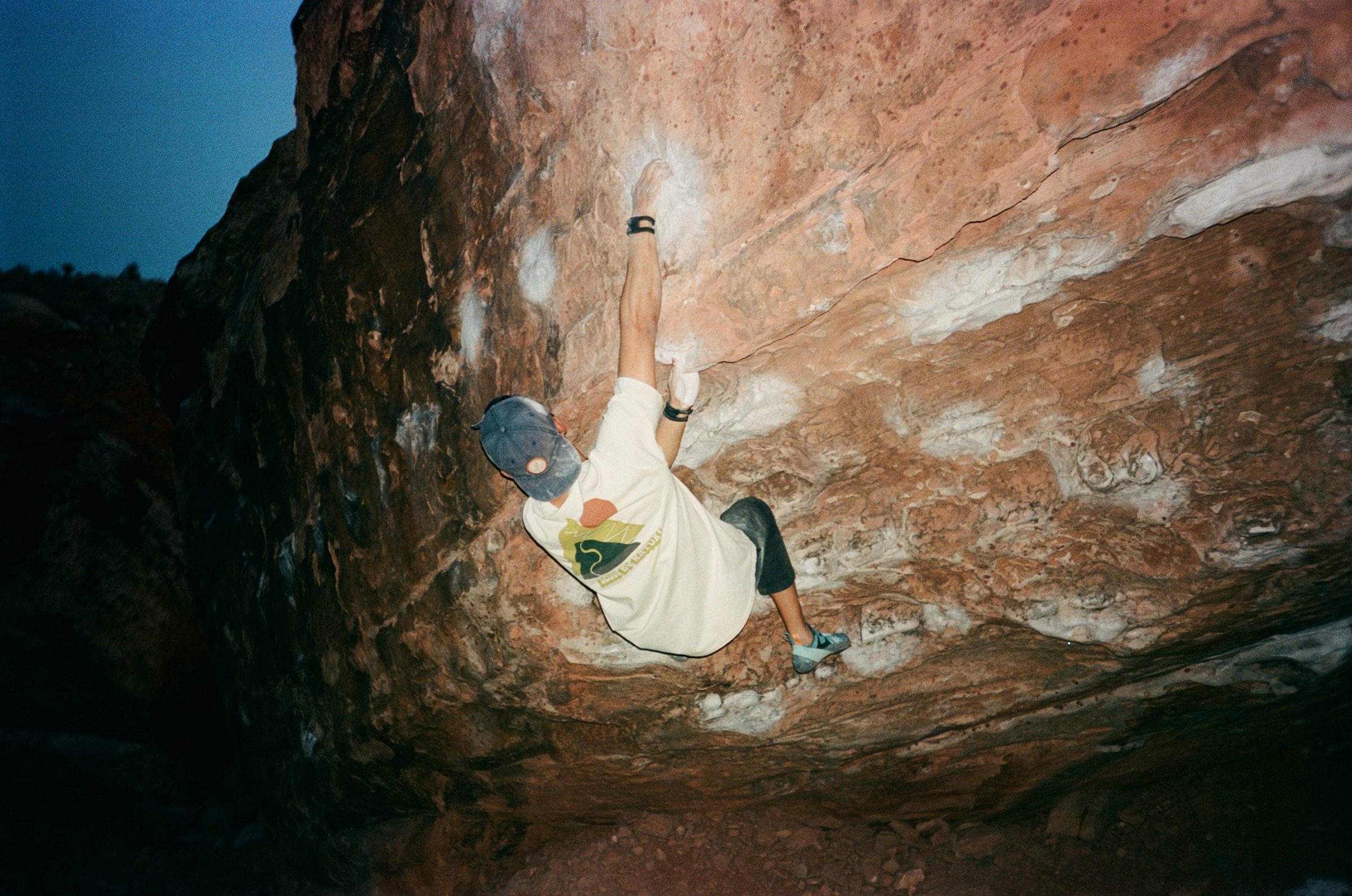 a climber on a red sandstone overhang at dusk
